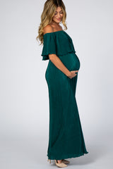 woman wearing a dark green off-the-shoulder maternity maxi dress, showing her baby bump and smiling