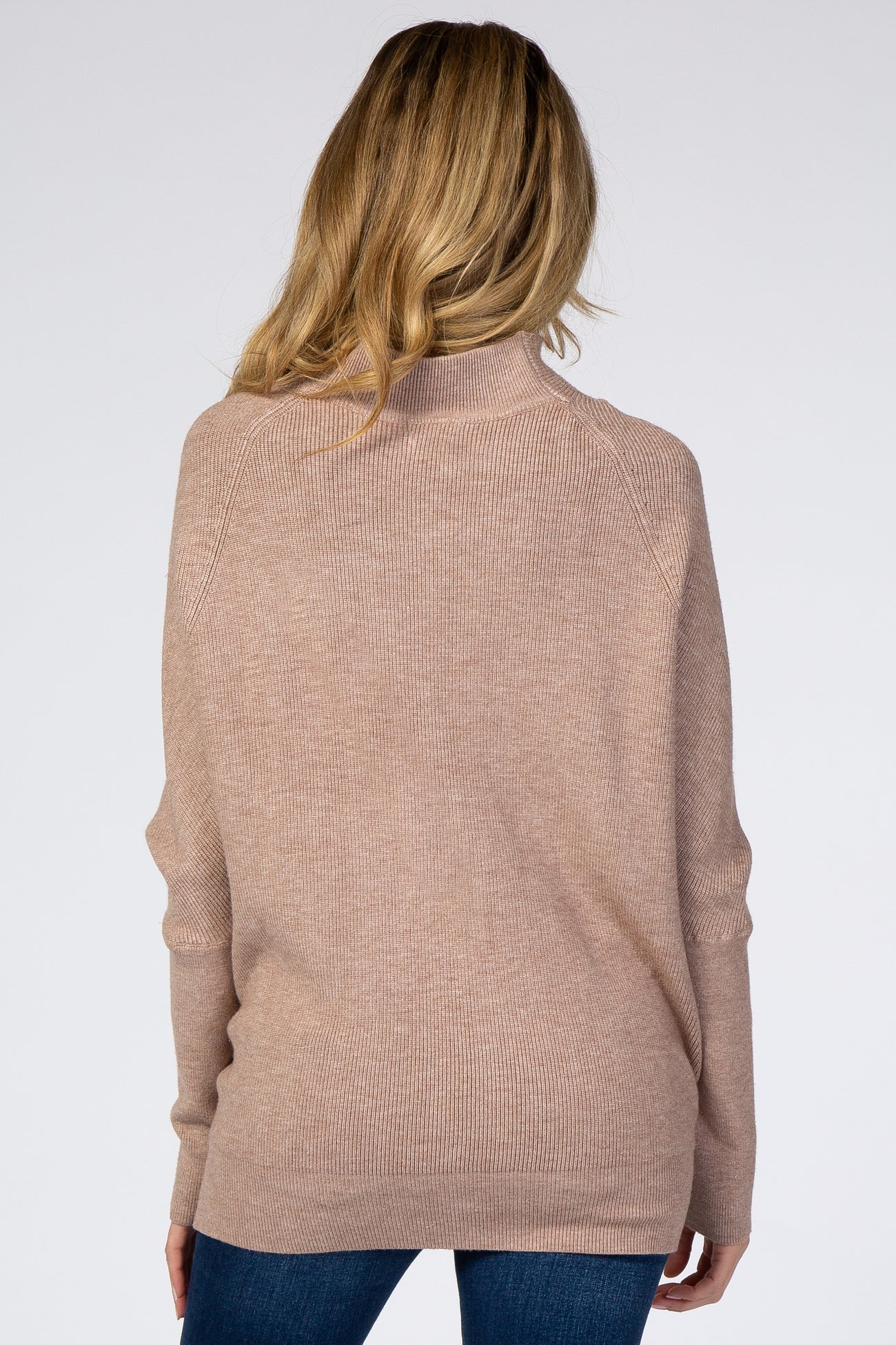 woman wearing a soft beige oversized maternity sweater, back view, with a relaxed fit and ribbed detail