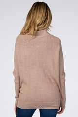 woman wearing a soft beige oversized maternity sweater, back view, with a relaxed fit and ribbed detail