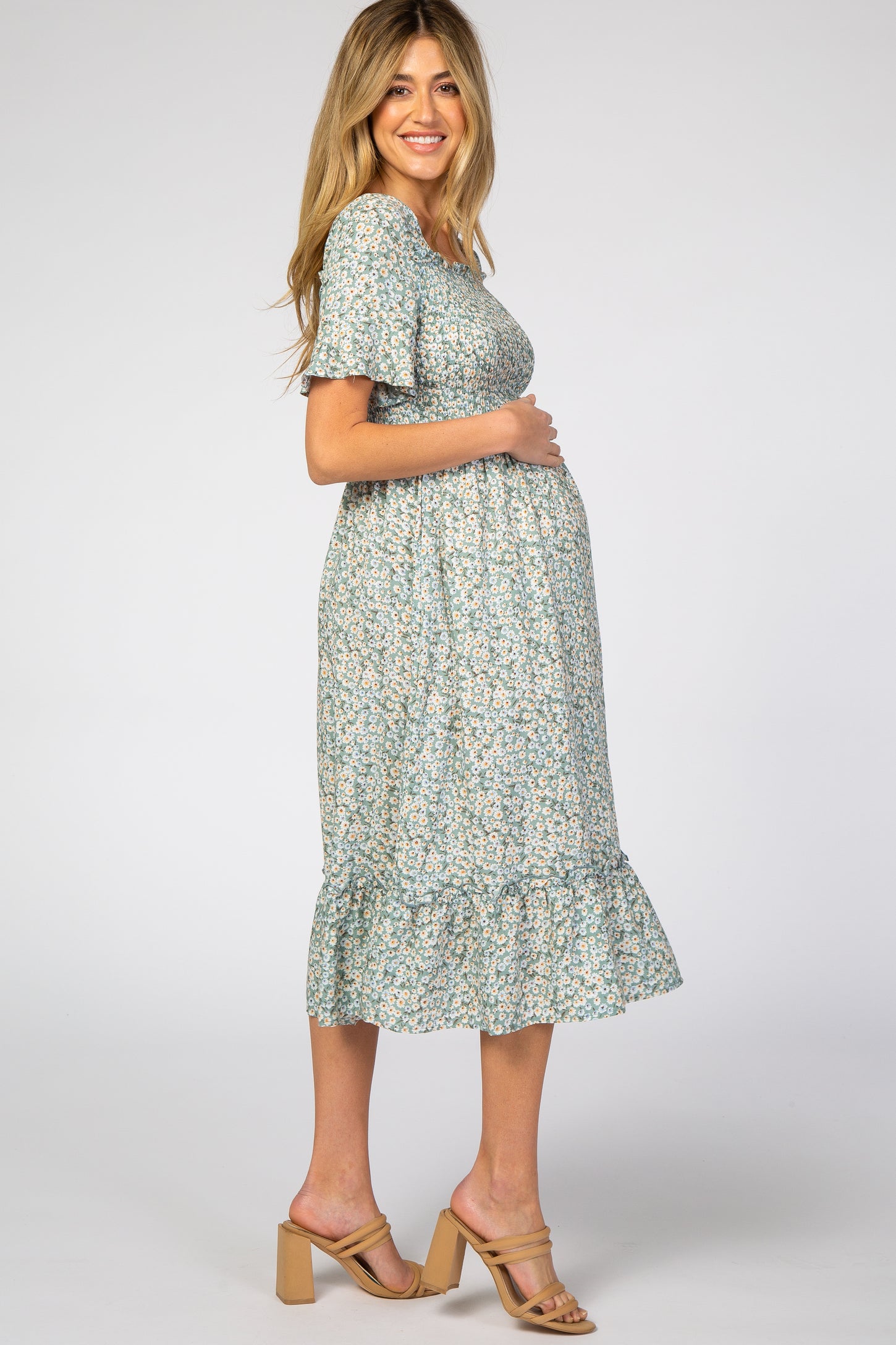 woman wearing a floral maternity dress with short sleeves and a ruffled hem, showcasing her baby bump