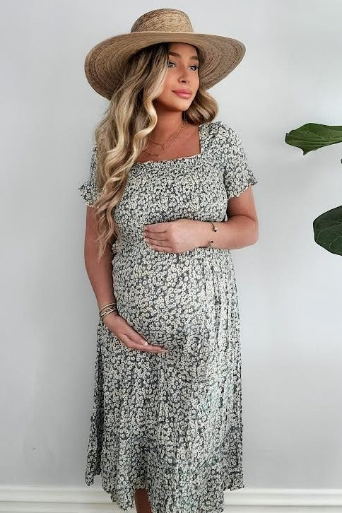 woman wearing a floral maternity dress with a square neckline and holding her baby bump