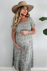 woman wearing a floral maternity dress with a square neckline and holding her baby bump