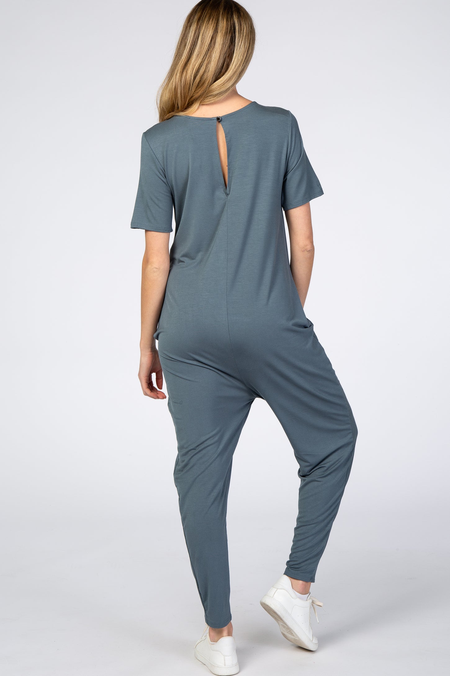 woman wearing a slate blue maternity jumpsuit with short sleeves and a back keyhole detail