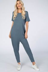 woman wearing a casual teal short sleeve jumpsuit with a relaxed fit and white sneakers