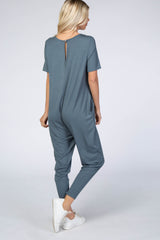 back view of a woman wearing a short sleeve slate blue maternity jumpsuit with white sneakers