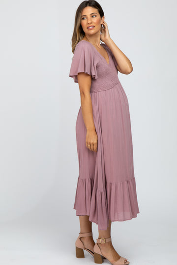 woman wearing a dusty rose maternity dress with flutter sleeves and a tiered hem, showcasing her baby bump