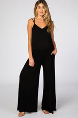 woman wearing a black maternity jumpsuit with wide legs and adjustable straps, showing her baby bump