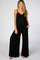 woman wearing a black maternity jumpsuit with wide legs and adjustable straps, showing her baby bump
