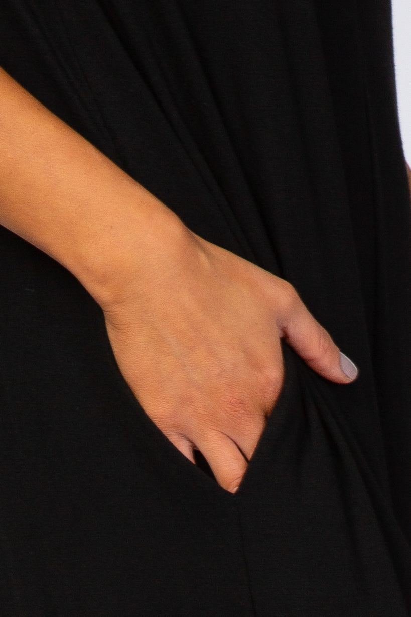 Close up of a person's hand resting in the side pocket of a black dress or garment