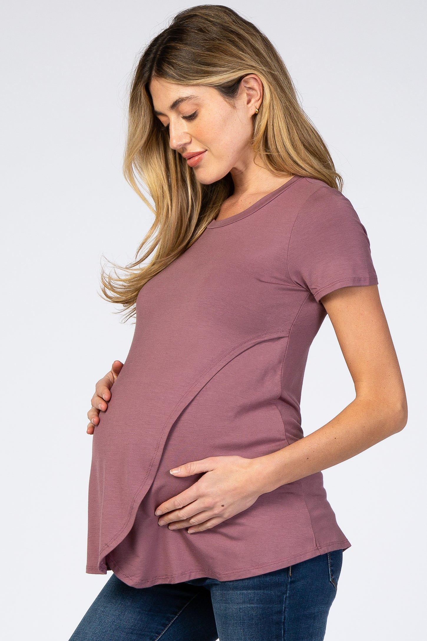 woman wearing a mauve short sleeve maternity top and holding her baby bump