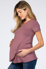 woman wearing a mauve short sleeve maternity top and holding her baby bump
