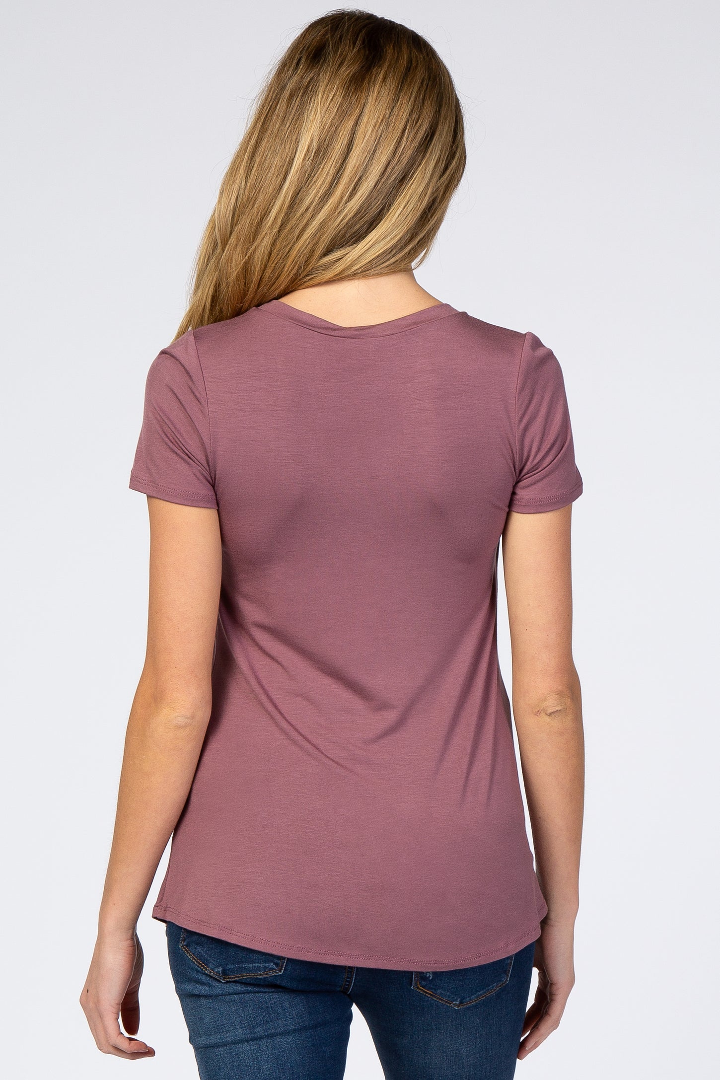 woman wearing a mauve short sleeve maternity top, viewed from the back, paired with blue jeans
