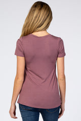 woman wearing a mauve short sleeve maternity top, viewed from the back, paired with blue jeans