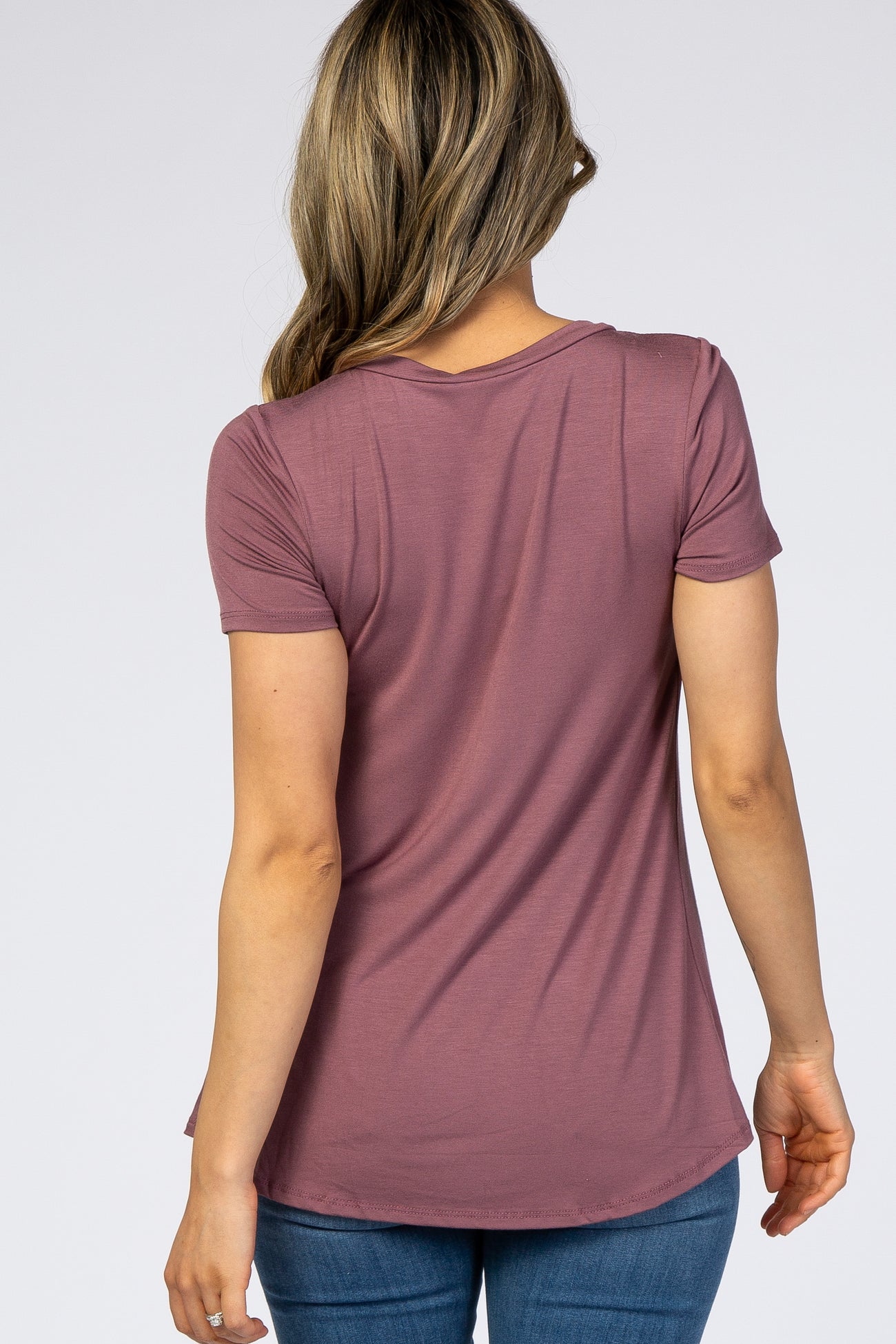 woman wearing a mauve short sleeve top from the back, styled with a curved hem and paired with blue jeans