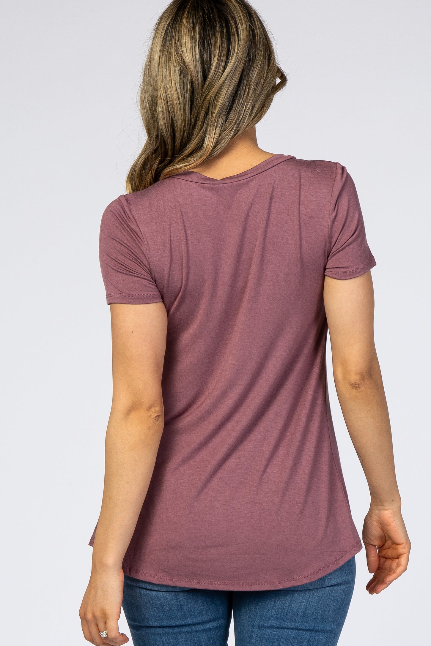 woman wearing a mauve short sleeve top from the back, styled with a curved hem and paired with blue jeans