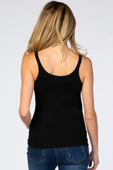 Back view of a woman with blonde hair wearing a black ribbed tank top and blue jeans