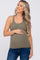 Smiling pregnant woman wearing an olive green ribbed maternity tank top and blue jeans