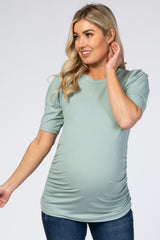 blonde woman wearing a sage green ribbed maternity top with short puff sleeves and side ruching