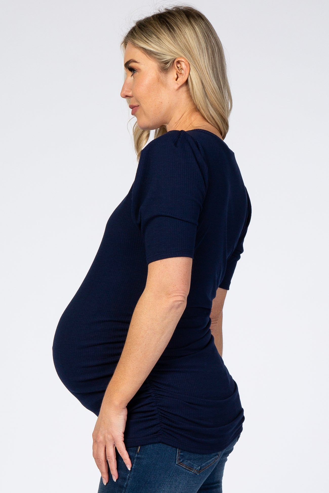 woman wearing a navy blue short sleeve maternity top with ruching and a visible baby bump