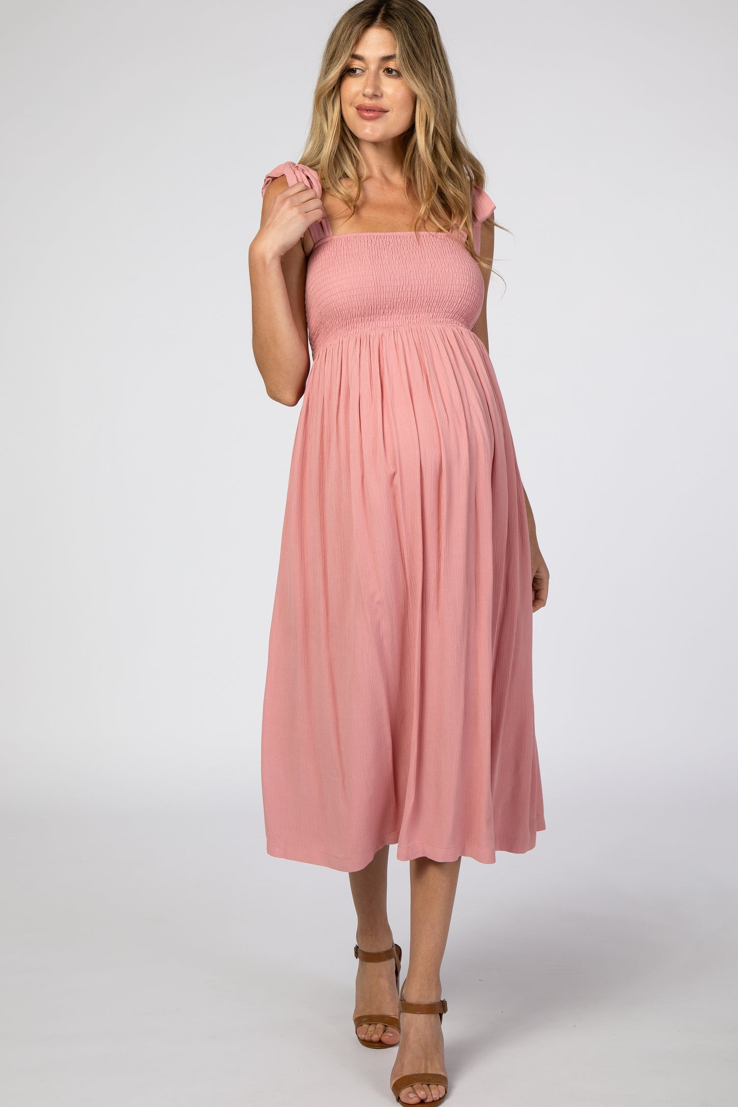 woman wearing a pink smocked maternity dress with ruffled straps and a visible baby bump