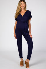 woman wearing a navy blue maternity jumpsuit with a tie waist and short sleeves, showcasing her baby bump