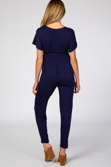woman wearing a navy blue maternity jumpsuit with short sleeves and a fitted waist, seen from the back