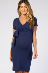 woman wearing a navy short sleeve maternity dress with a tie detail at the waist and a visible baby bump