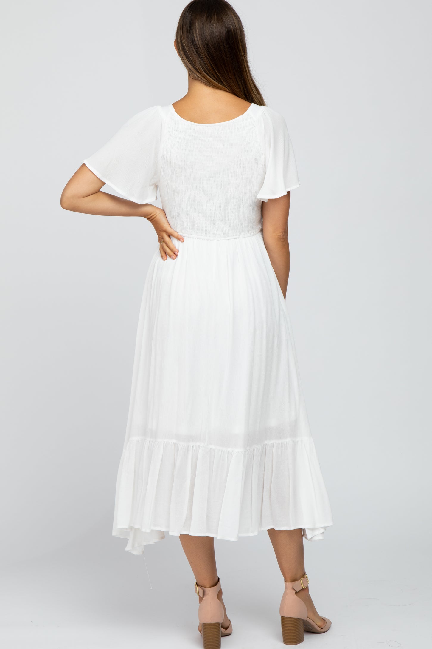woman wearing a white maternity dress with short sleeves and a tiered skirt, showing a comfortable and flowy design