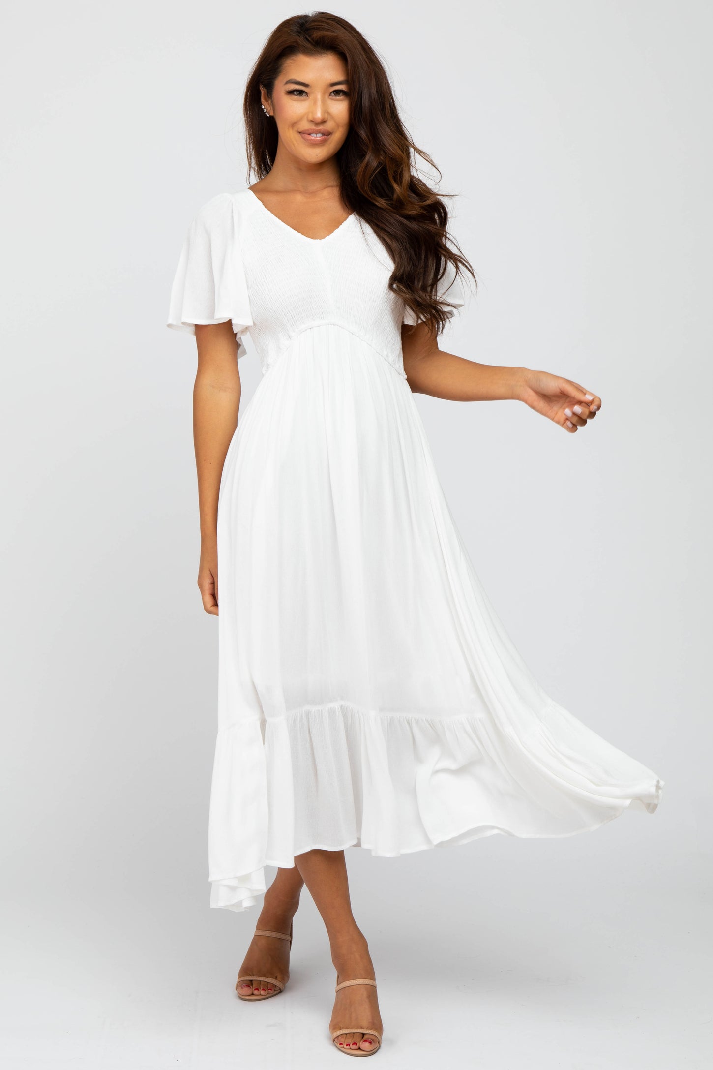 woman wearing a white flutter sleeve midi dress with a textured bodice and flowing skirt