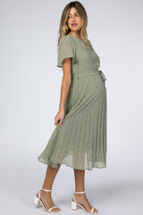 pregnant woman in a sage green floral maternity midi dress with short sleeves and white block heel sandals