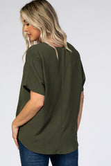 Back view of a woman with blonde hair wearing an olive green short sleeve blouse and blue jeans