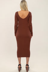 woman wearing a rust brown ribbed long sleeve maternity dress with a deep v-back, showing off her baby bump