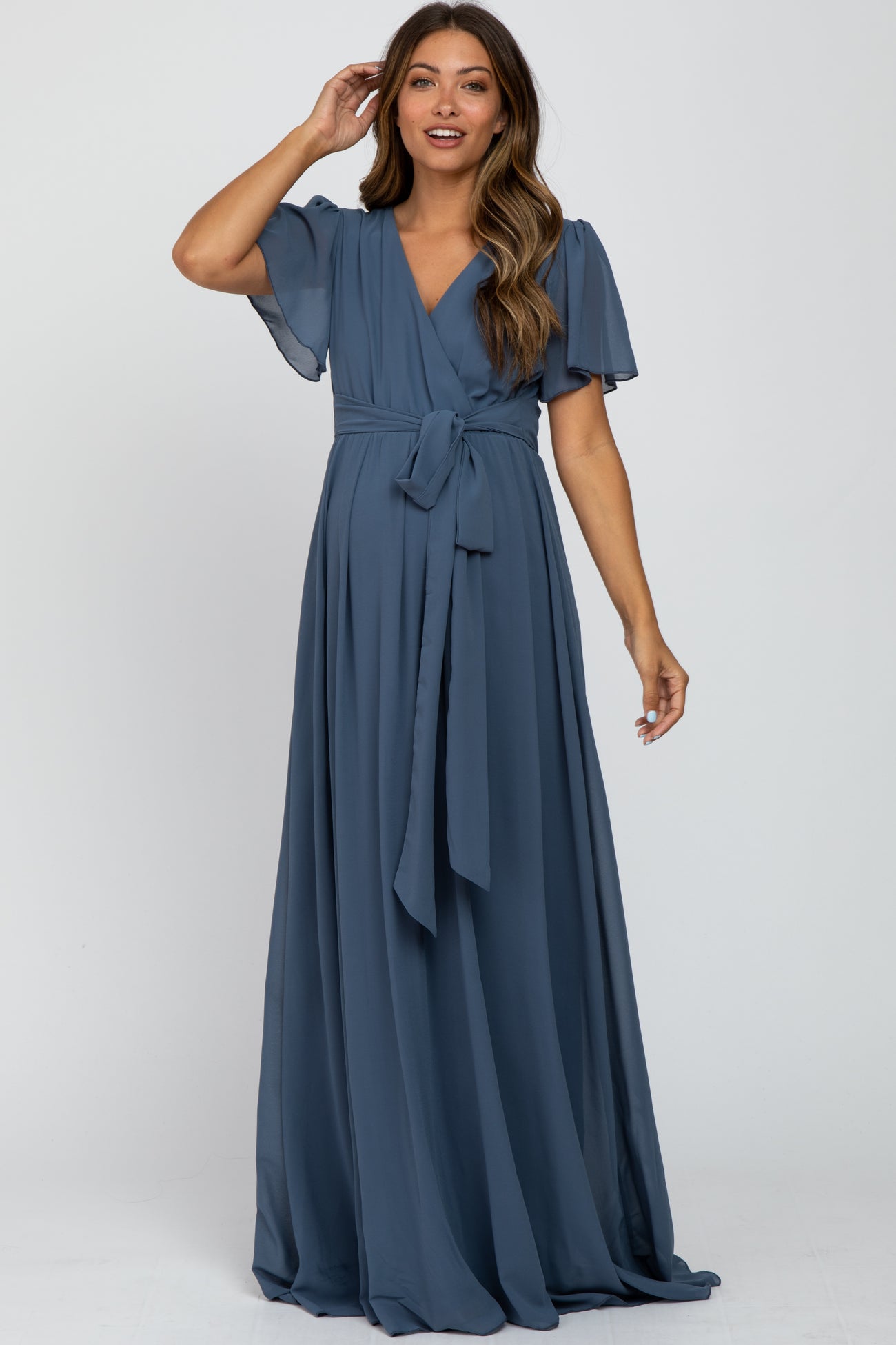 woman wearing a blue maternity wrap dress with flutter sleeves and a tie waist