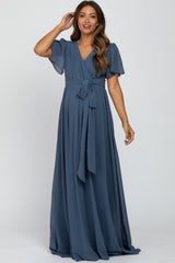 woman wearing a blue maternity wrap dress with flutter sleeves and a tie waist