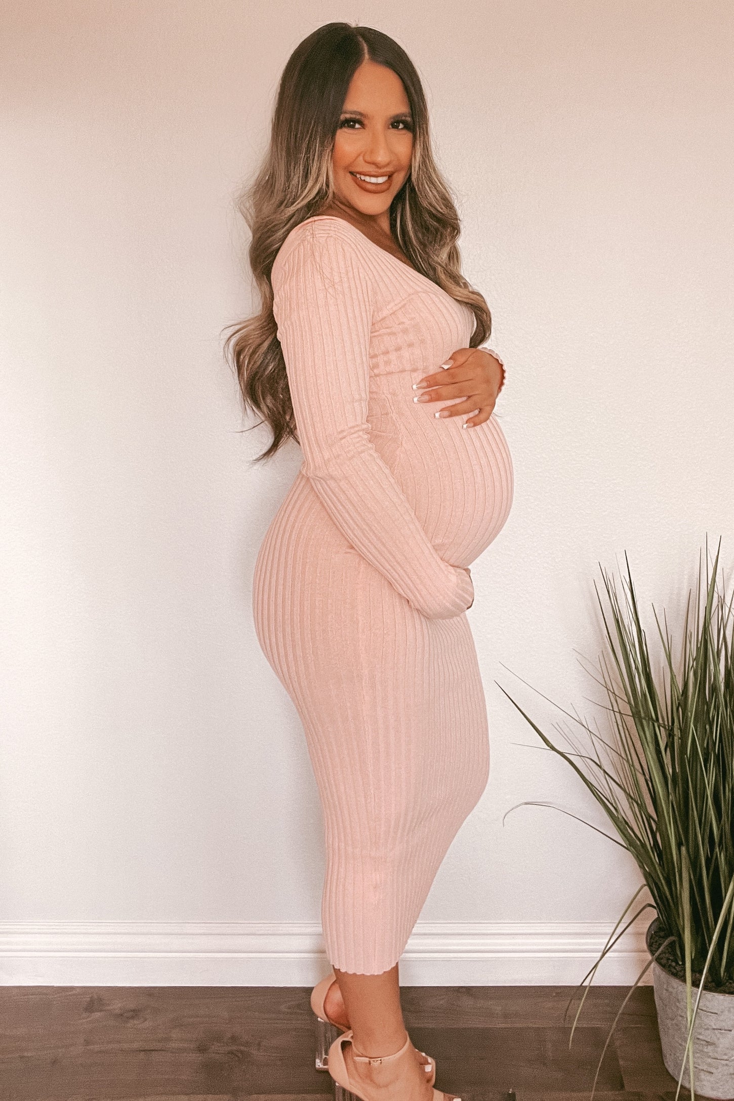 woman wearing a light pink ribbed maternity dress with a fitted silhouette and a visible baby bump