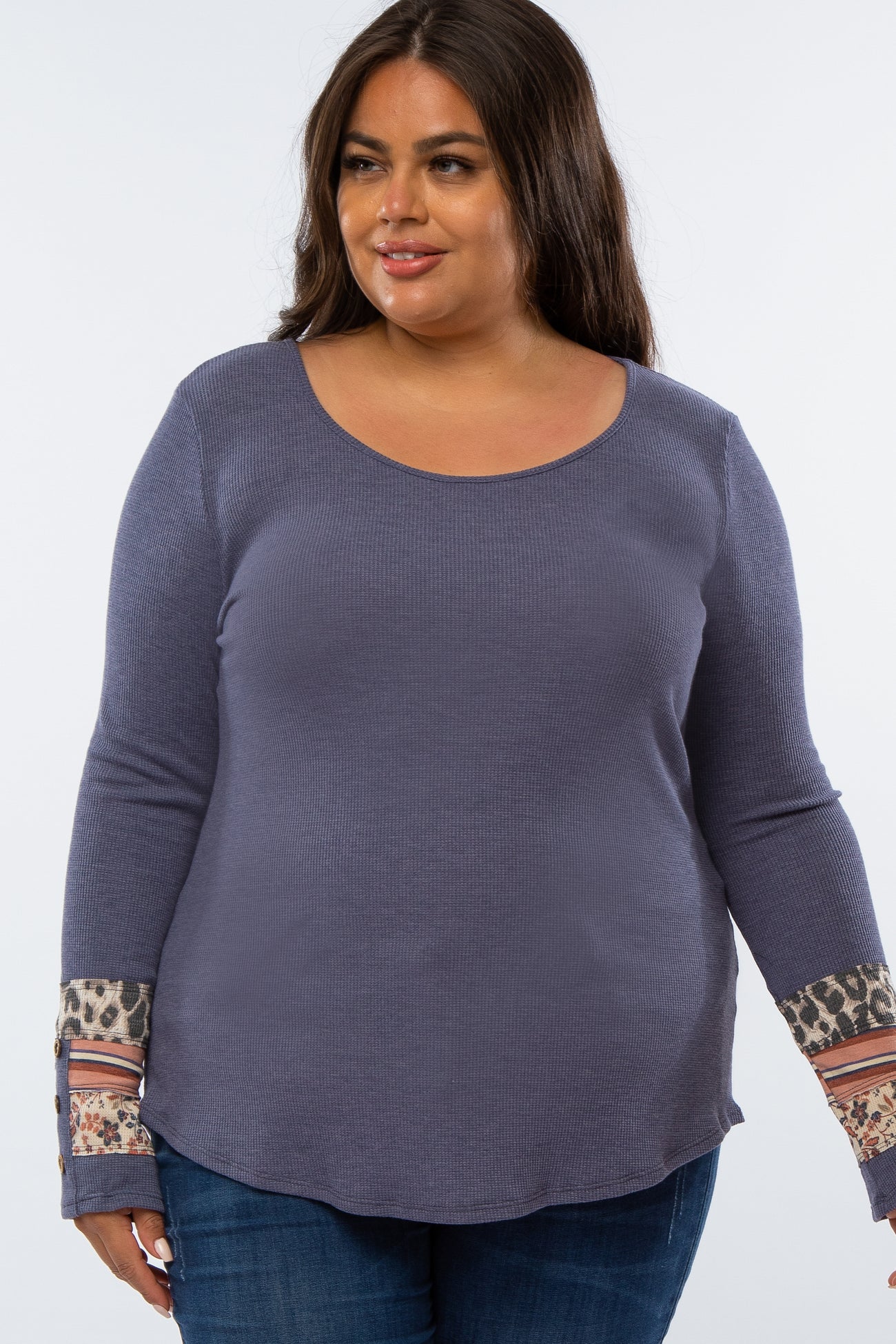 Plus size woman wearing a blue waffle knit long sleeve top with leopard print and floral patterned cuffs