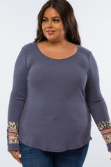 Plus size woman wearing a blue waffle knit long sleeve top with leopard print and floral patterned cuffs