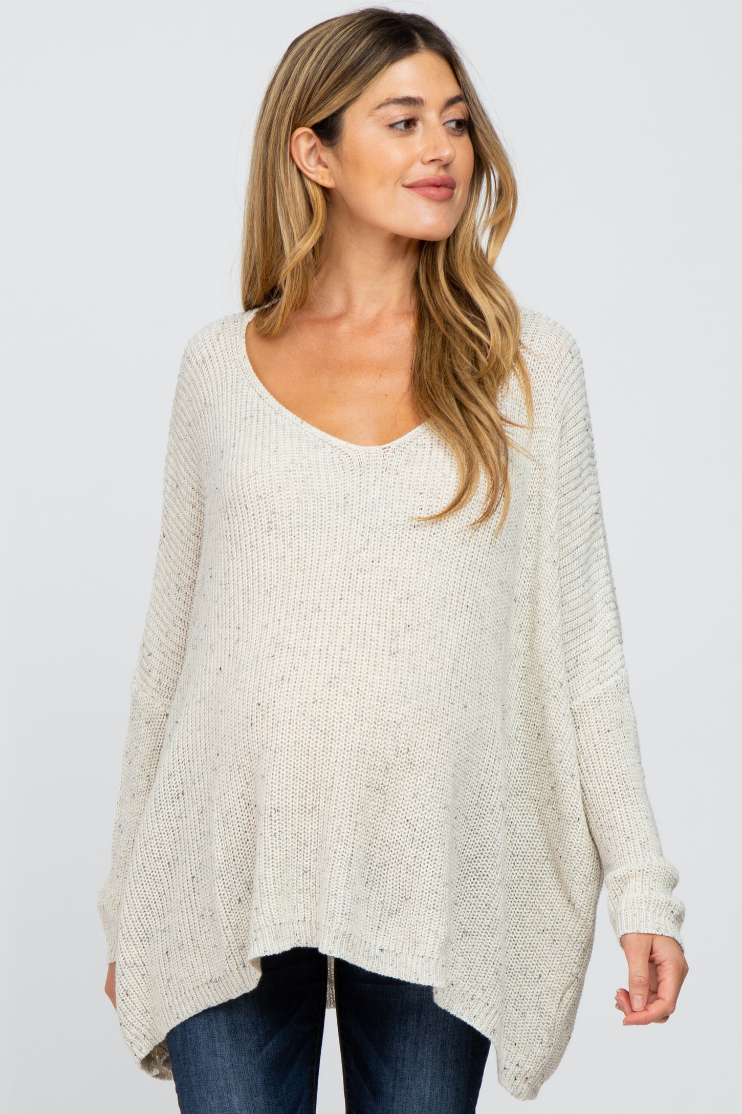 woman wearing a light gray maternity sweater with a scoop neckline and loose fit, showcasing her baby bump