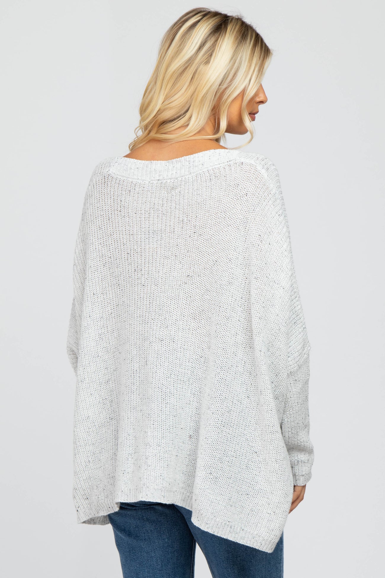woman wearing a light gray oversized knit sweater with a relaxed fit and dropped shoulders, viewed from the back