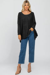 woman wearing a dark gray long sleeve oversized sweater with side slits and blue high-waisted cropped jeans