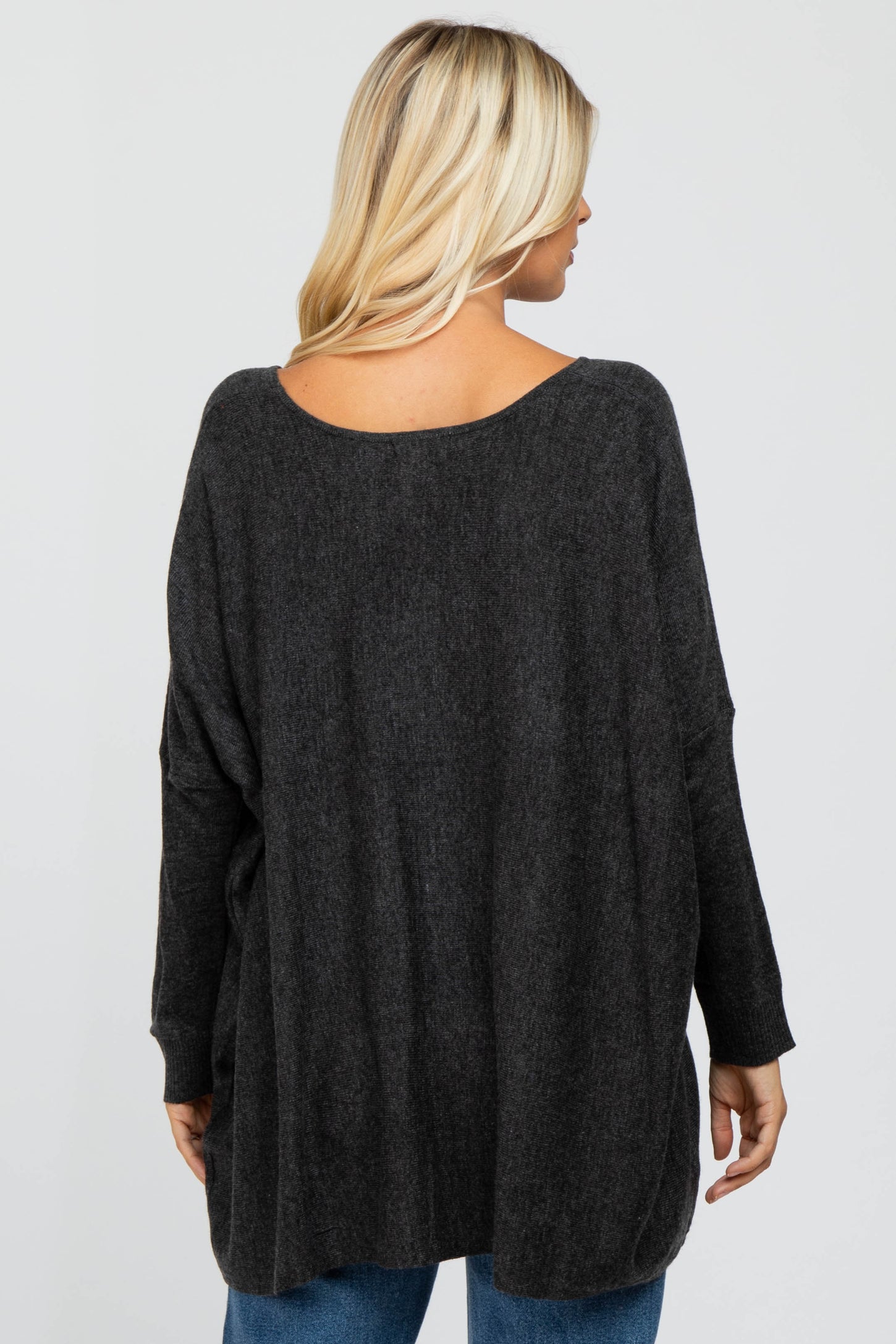 woman wearing a dark gray oversized sweater, viewed from the back, with long sleeves and a relaxed fit