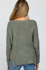 woman wearing a green open knit maternity sweater, viewed from the back, paired with blue jeans