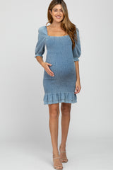 woman wearing a light blue maternity dress with a smocked bodice and ruffle hem, showing her baby bump