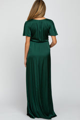 woman wearing a dark green satin maternity maxi dress, showing the back view and relaxed fit