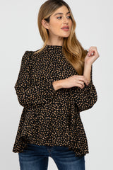 woman wearing a black maternity top with tan polka dots and puff sleeves, styled with blue jeans