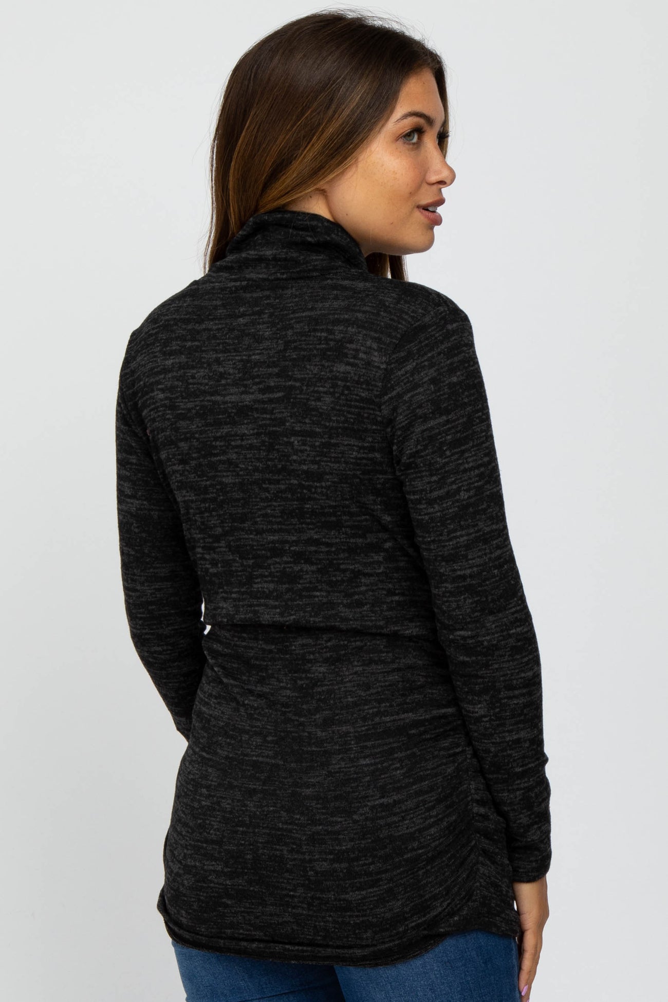 woman wearing a charcoal grey marl turtleneck sweater and blue jeans viewed from the back