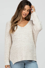 woman wearing a light beige loose knit maternity sweater with a v-neck and long sleeves