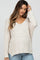 woman wearing a light beige loose knit maternity sweater with a v-neck and long sleeves