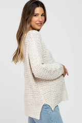 woman wearing a cream knitted maternity sweater and holding her baby bump