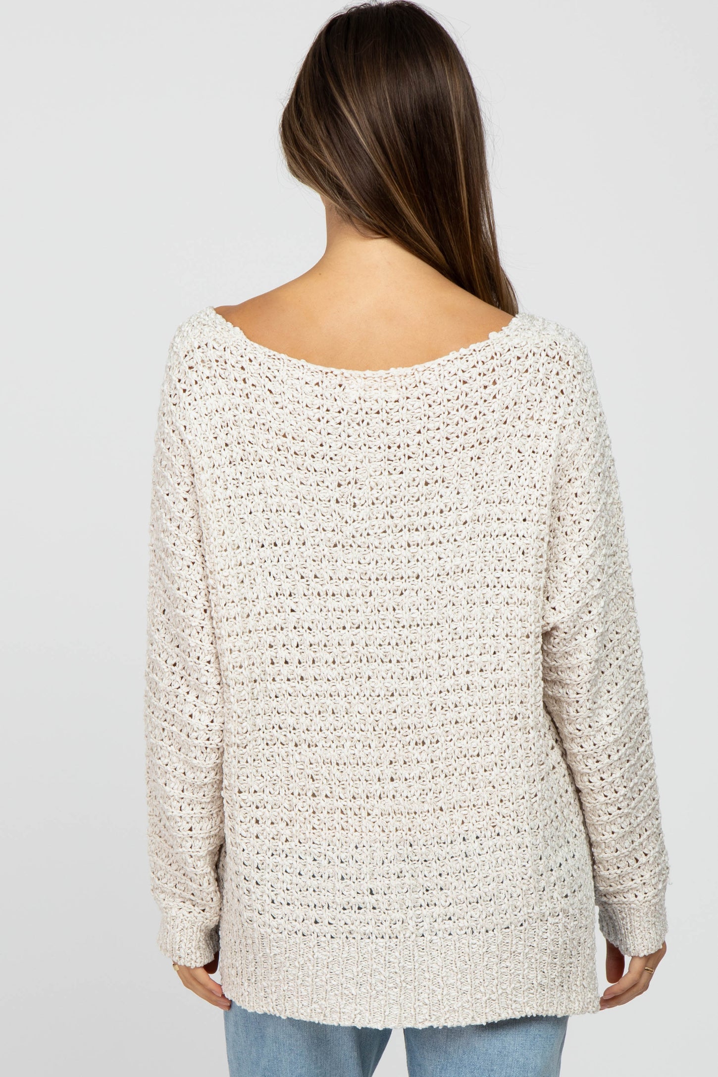 woman wearing a light beige open-knit maternity sweater with a relaxed fit and wide neckline, shown from the back